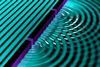 An illustration showing a regular arrangement of parallel waves that are broken into concentric ones as they pass through two narrow openings in a barrier